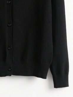 Detalle inferior del cardigan negro básico con terminación acanalada.