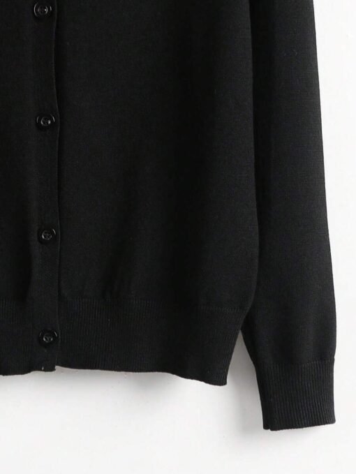 Detalle inferior del cardigan negro básico con terminación acanalada.