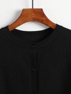 Detalle del cuello redondo del cardigan negro básico.