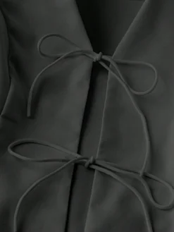 Detalle del escote y los nudos decorativos del conjunto negro casual