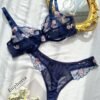 Set de lencería azul con bordado floral transparente sobre superficie blanca.