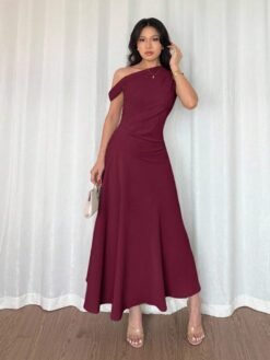 Modelo luciendo vestido elegante asimétrico rojo violeta largo con bolso.